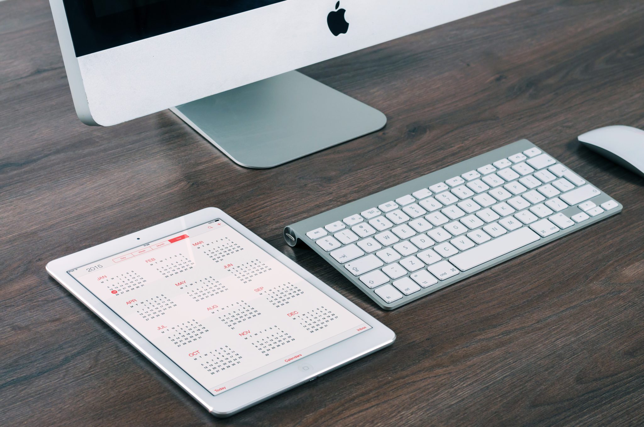 tablet mit kalender neben imac mit tastatur und maus